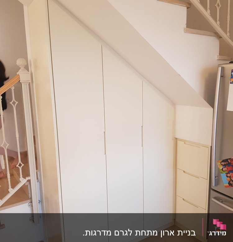 ארון לבן מתחת למדרגות עם דלתות משופעות